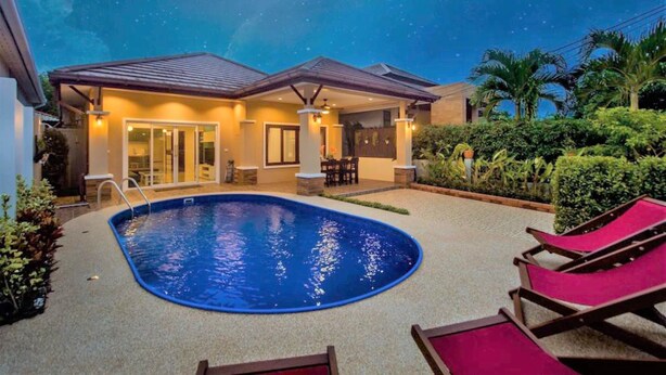 Propiedad residencial con piscina, sillas de descanso y un patio cubierto.