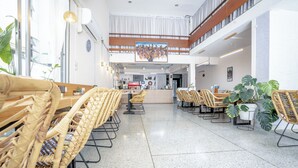 A spacious lobby with wicker furniture, a reception desk, and a large window allowing natural light. - Sabai house (Chiang Mai)