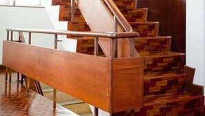 A staircase with a wooden finish and metal handrails, leading to a dark wooden door. - Sabai house (Chiang Mai)
