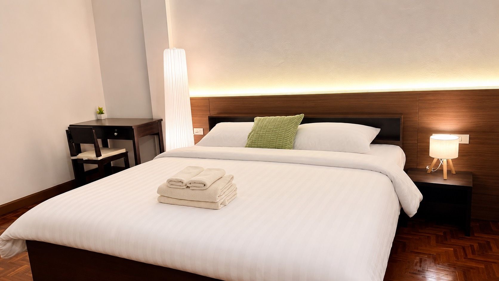 Habitación de hotel con una cama grande, una mesita de noche y una lámpara de pared.
