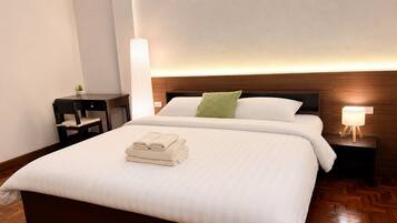 Habitación de hotel con una cama grande, una mesita de noche y una lámpara de pared.