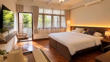 Habitación de hotel con una cama grande, un escritorio, una silla y un ventanal con cortinas.