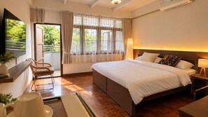 A hotel room with a large bed, a desk, a chair, and a window with curtains. - Sabai house (Chiang Mai)