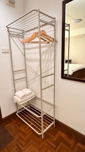 A metal storage unit with shelves and a hanging rack, located in a room with a wooden floor and a mirror on the wall. - Sabai house (Chiang Mai)