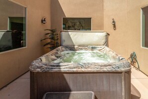 A hot tub in a room with a large window, a painting on the wall, and a plant. - Charlotte: Large Groups + Private Hot Tub + Roof Top Deck (Hurricane)