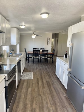 A modern kitchen with white cabinets, a dining area with a wooden table and chairs, and a ceiling fan. - "No Worries" less than 10 minutes from Lake Texoma and Choctaw Casino (Mead)
