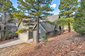 Une maison à deux étages, dotée d’un toit en pente, d’un garage et d’une allée menant à la porte d’entrée.