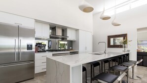 A modern kitchen with a large island, stainless steel appliances, and bar stools.