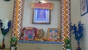 A room with a decorative shrine, a clock, and framed pictures on the wall. - Hotel Fun Park Sanand (Sanand)