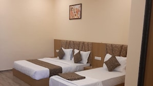 A hotel room with two beds, each with a headboard and pillows. - Hotel Fun Park Sanand (Sanand)