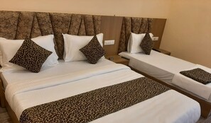 A hotel room with two single beds, each with a patterned bedspread and matching pillows. - Hotel Fun Park Sanand (Sanand)