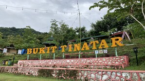 Una señal con el texto 'BUKIT TINATAR' y 'PROGRAM KEMERJIAN WILAYAH', indicando un lugar o nombre de programa.