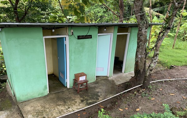A small, green structure with two doors, a wooden stool, and a sign.