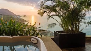 Un jacuzzi con vistas a un paisaje costero y una planta grande en maceta.