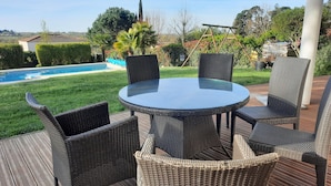A round glass table with wicker chairs on an outdoor deck.