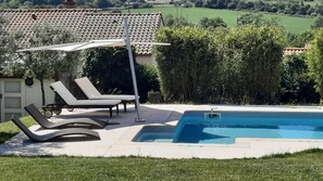 A pool area with lounge chairs and a pergola.
