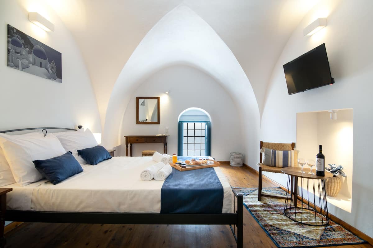 Ein Schlafzimmer mit einem Bett, einem Frühstückswagen, einem Tisch mit einer Flasche und einem an der Wand befestigten Fernseher.