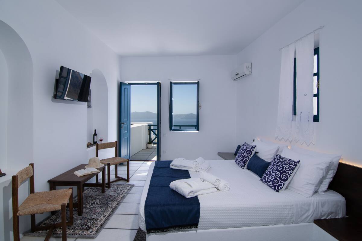Ein modernes Schlafzimmer mit einem großen Bett, einem Schreibtisch mit Stuhl und einem an der Wand befestigten Fernseher.