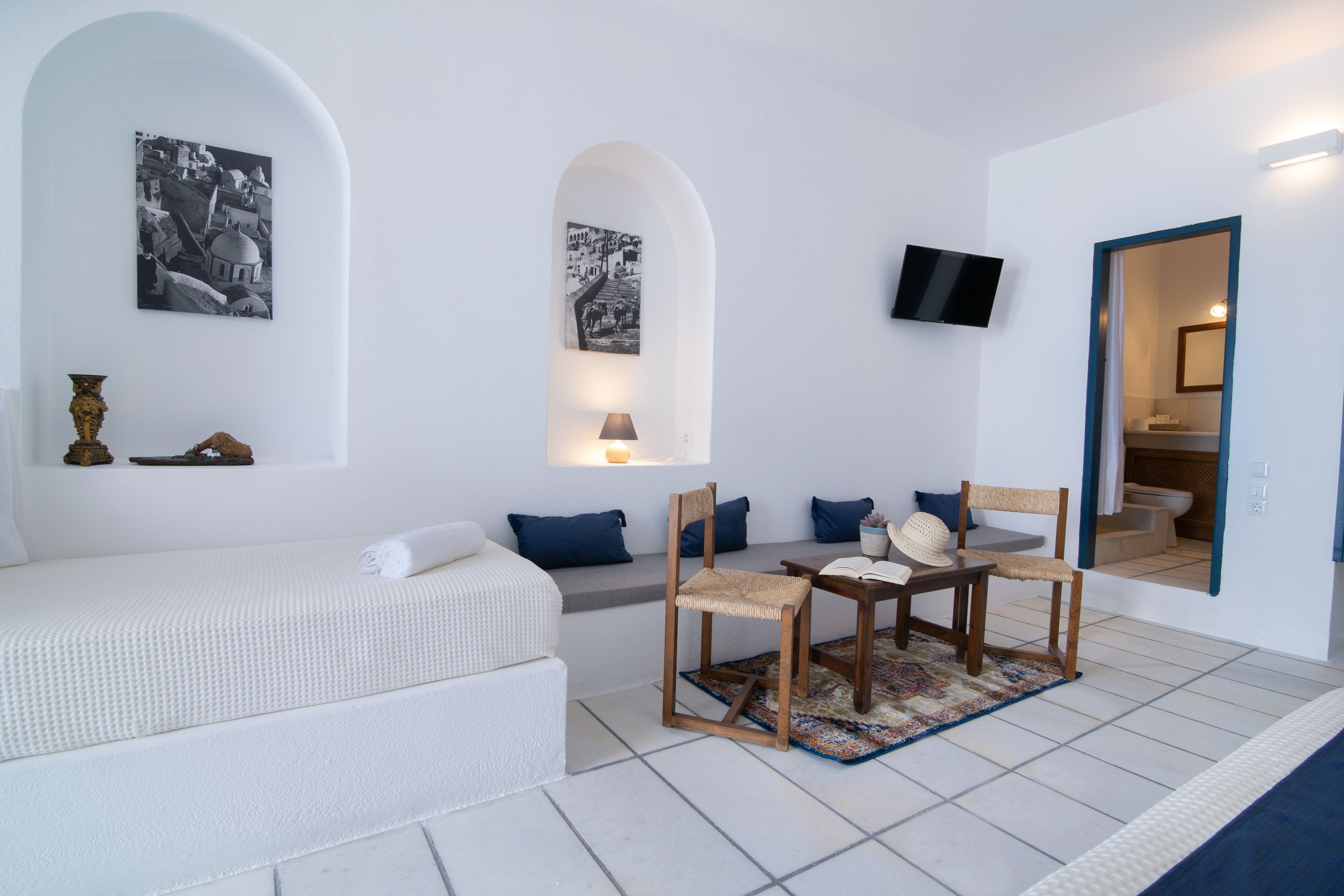 A modern, minimalist room with a white sofa, a small wooden table with chairs, and two wall-mounted picture frames.