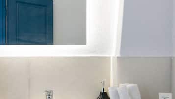 Une salle de bain avec un lavabo blanc, un meuble bleu et un miroir qui reflète le meuble.