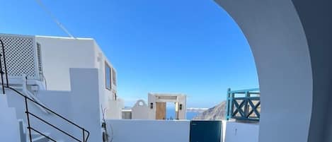 A modern white building with a staircase, potted plants, and a view of the sea.
