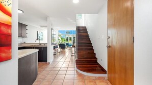 Una cocina moderna con una isla curva, una escalera de madera y vistas a un comedor.
