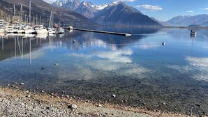 A calm lake with boats, clear water, and mountains in the background. - Lakeside Apartment with a swimming pool, free parking, and free Wi-Fi (Domaso)
