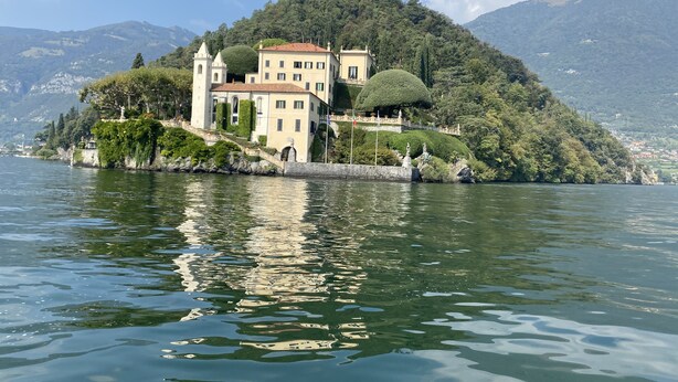 A lakeside castle with a tower, surrounded by lush greenery and a clear sky. - Lakeside Apartment with a swimming pool, free parking, and free Wi-Fi (Domaso)
