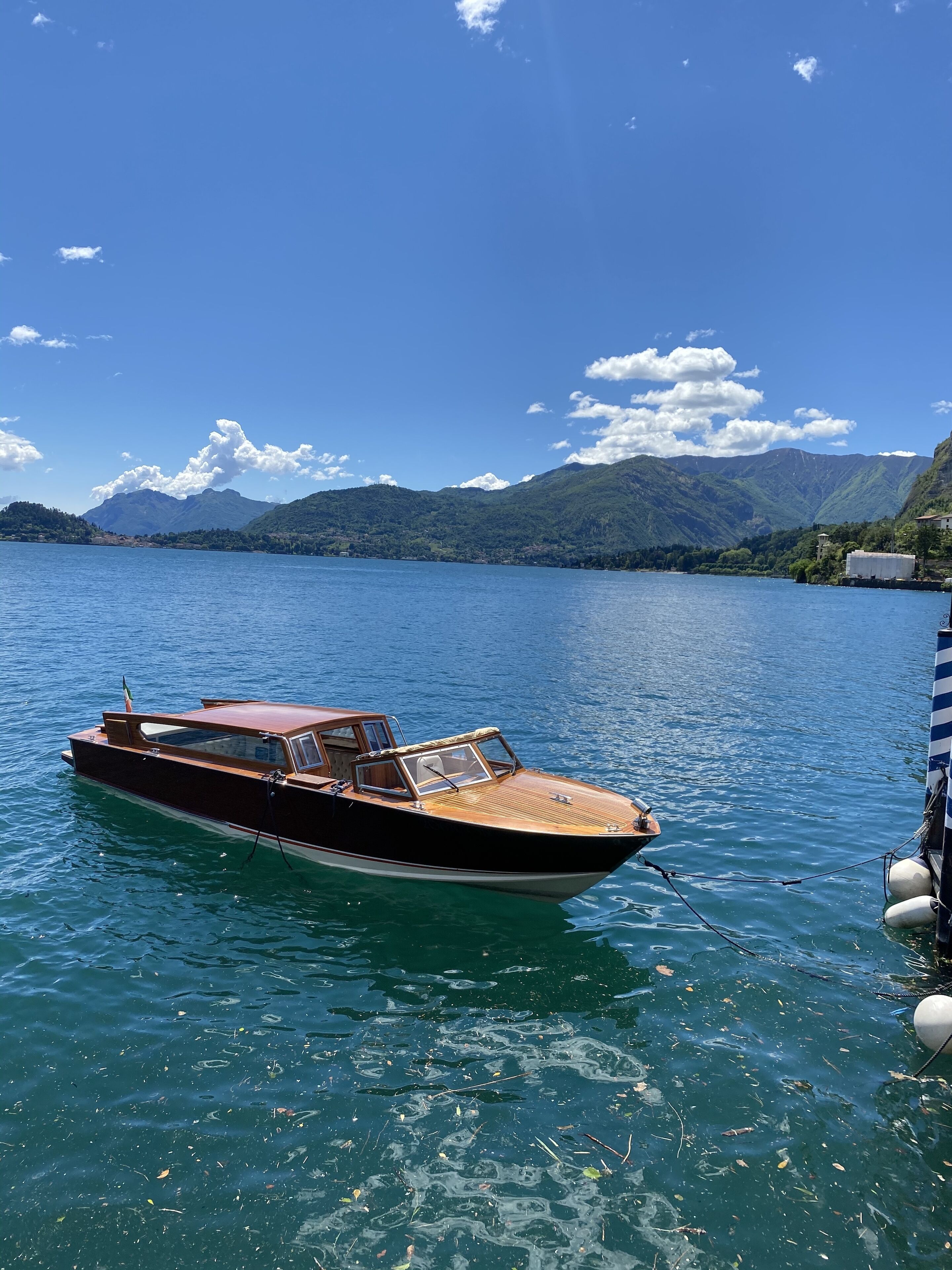 A wooden boat docked at a pier with a mountainous backdrop.
