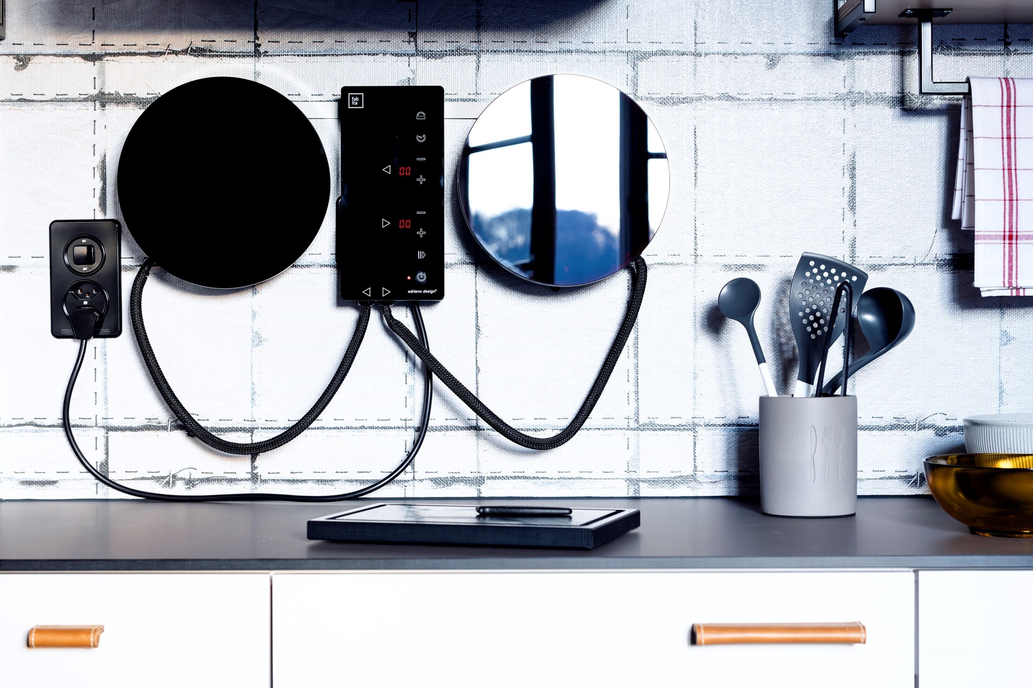 Une cuisine au design moderne, dotée d’un appareil électroménager noir de forme circulaire, d’un panneau de commande numérique et d’un pare-feu réfléchissant.