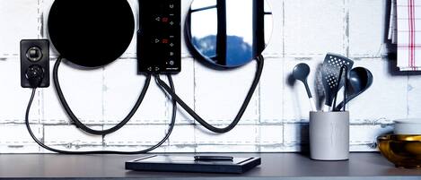 Une cuisine au design moderne, dotée d’un appareil électroménager noir de forme circulaire, d’un panneau de commande numérique et d’un pare-feu réfléchissant.