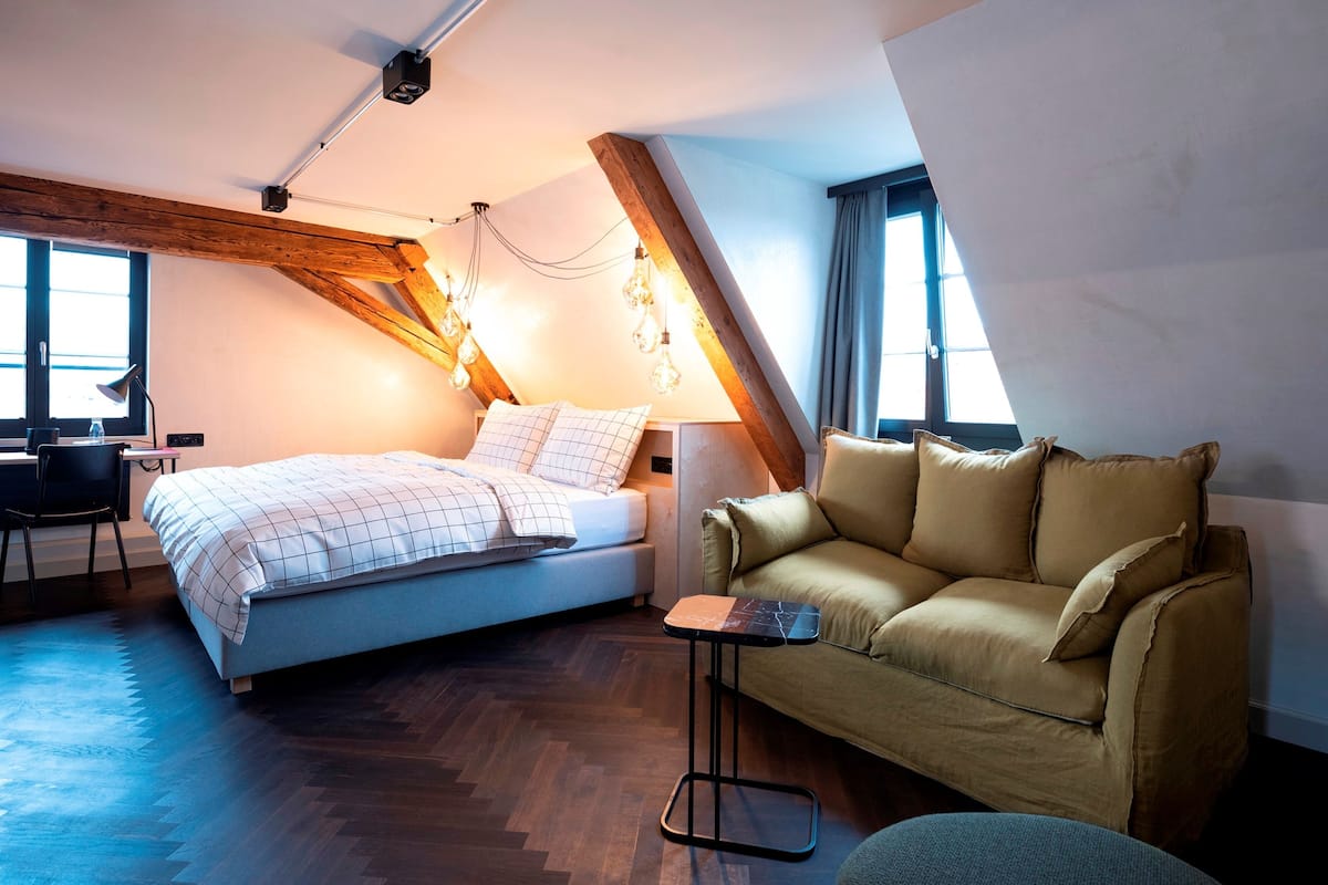 A bedroom with a bed, a sofa, a desk, and a chair.