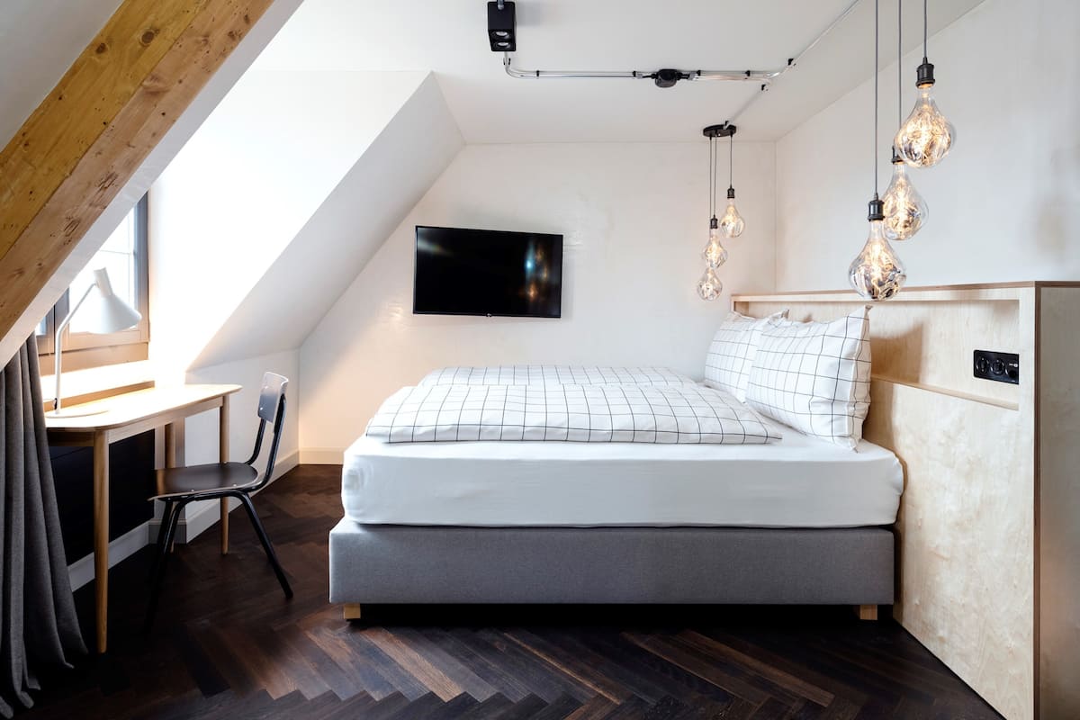 A modern bedroom with a bed, a desk, and a chair.