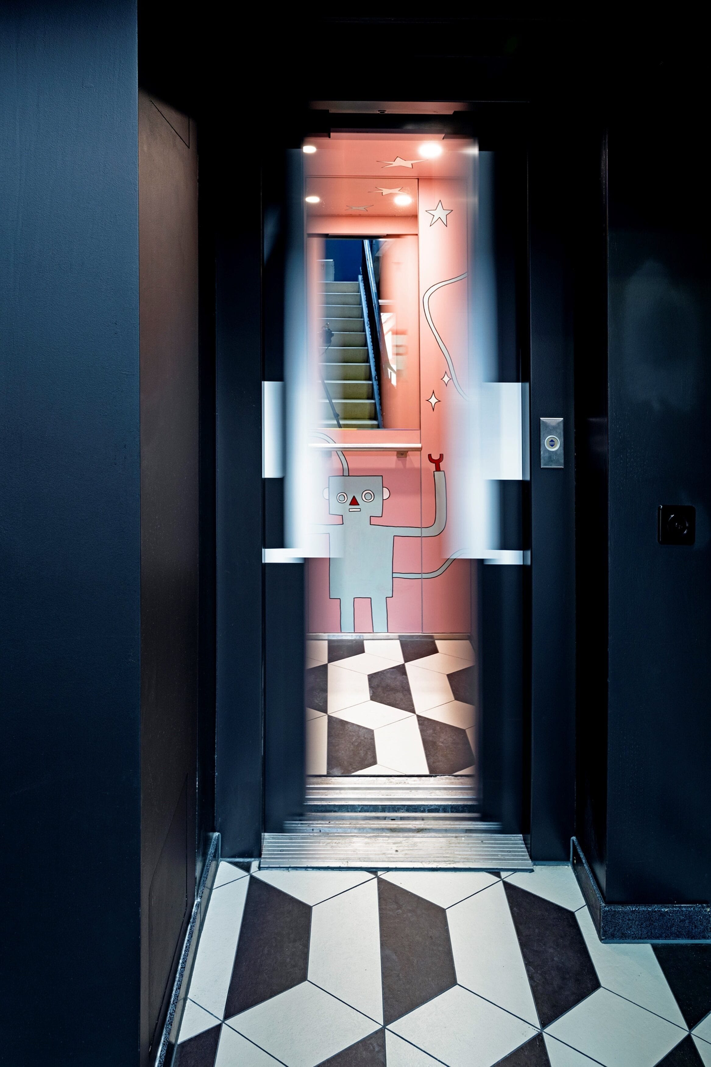 A modern elevator with geometric patterned floor tiles and a metallic handrail.