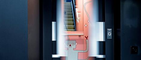 A modern elevator with geometric patterned floor tiles and a metallic handrail.