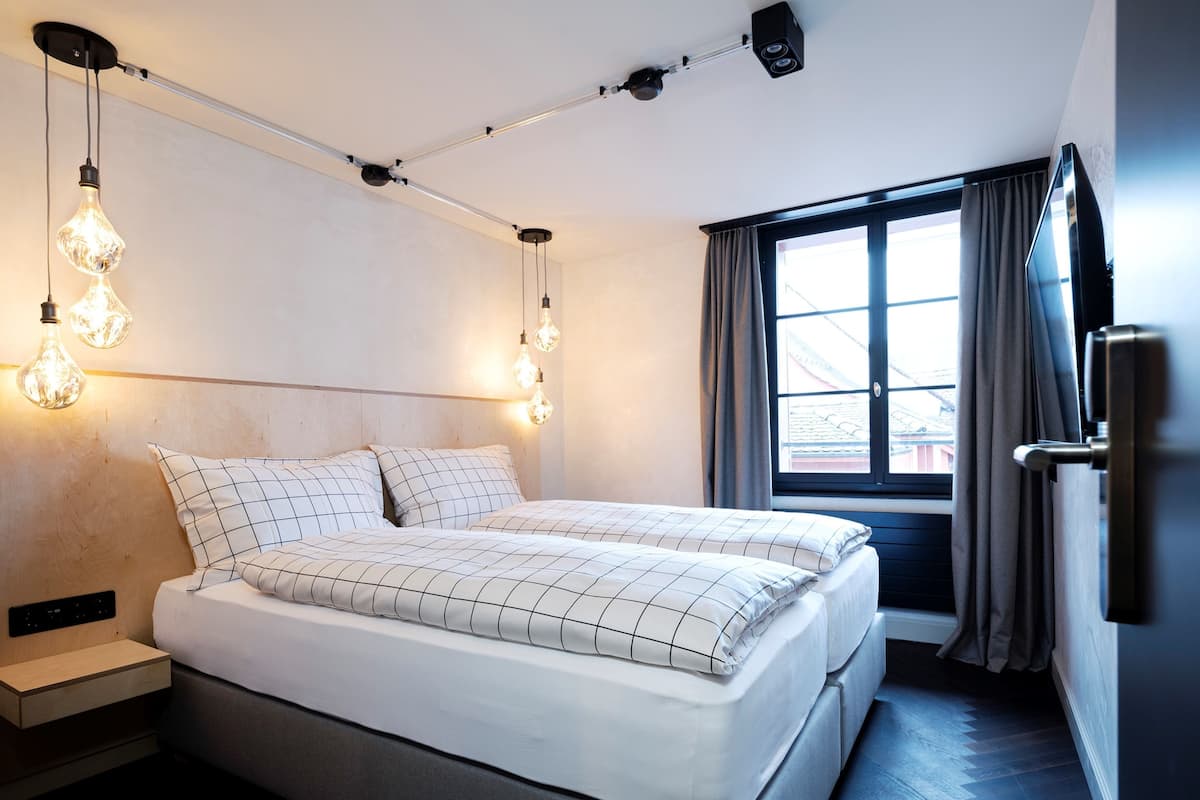 A modern bedroom with a bed, bedside tables, and a window with curtains.