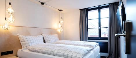 Une chambre à coucher moderne, avec un lit, des tables de chevet et une fenêtre avec des rideaux.