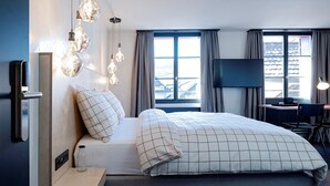 Une chambre d’hôtel moderne équipée d’un lit, d’un bureau et d’une télévision.