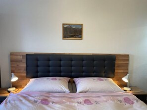 A bed with a wooden headboard, two bedside lamps, and a floral bedspread.