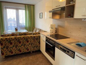 A compact kitchenette with a built-in oven, a coffee maker, and a dishwasher. There is a small dining area with a table and chairs.