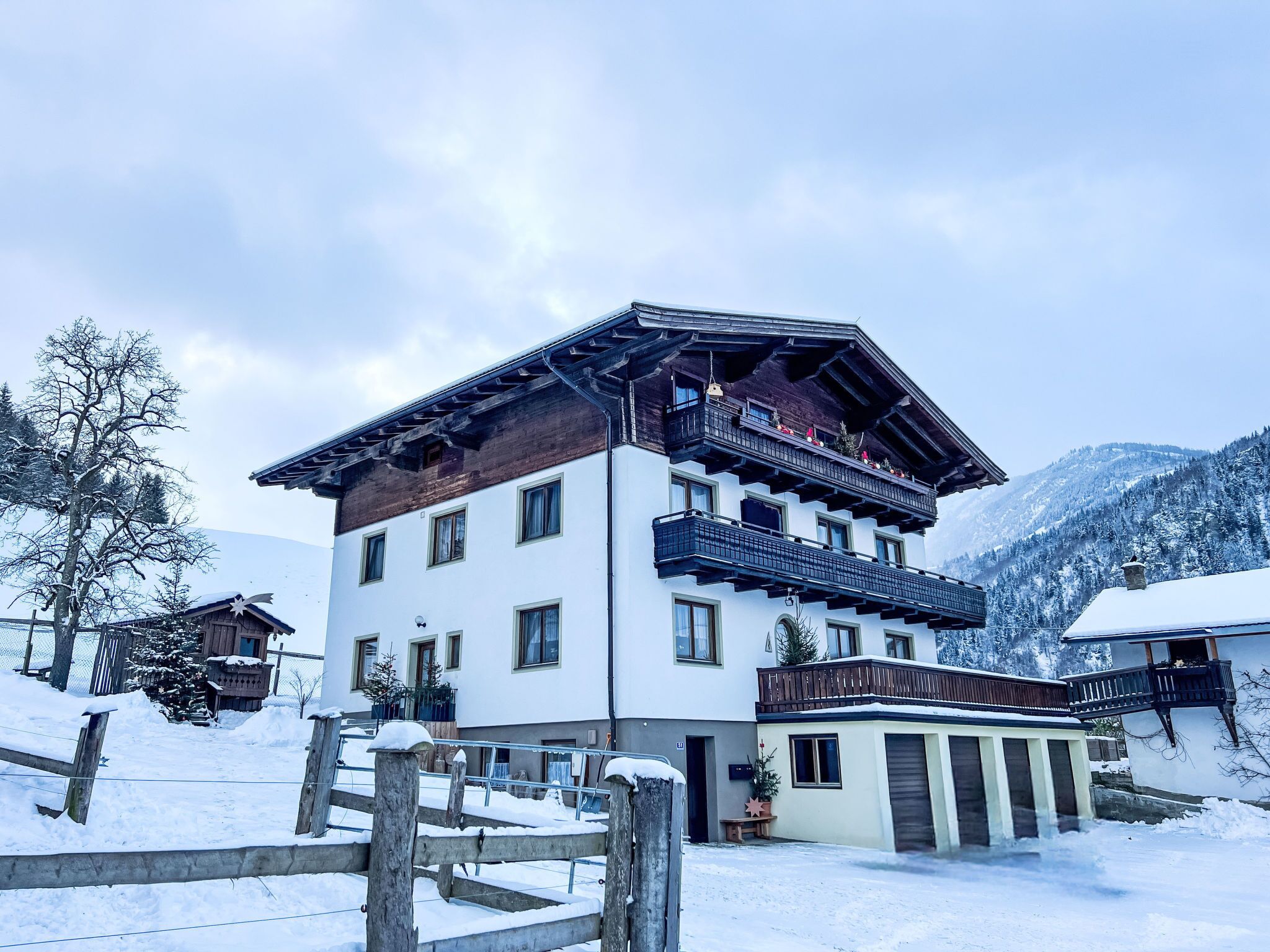 Ein mehrstöckiges Gebäude mit Balkonen, eine verschneite Landschaft und Berge im Hintergrund.