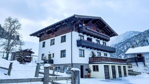 A multi-story building with balconies, a snow-covered landscape, and mountains in the background.