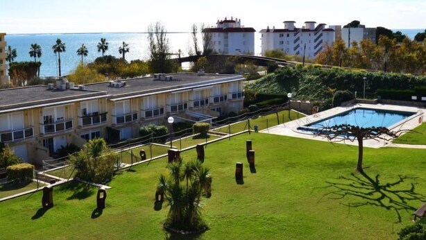 Un hotel con piscina en la azotea, césped bien cuidado y vista al mar.