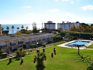 A hotel with a rooftop pool, a well-maintained lawn, and a view of the sea.