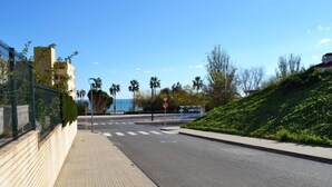 Una calle tranquila en la ciudad con acera, paso de peatones y vista al mar.