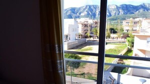 Un balcón con vista a una zona residencial, con edificios y montañas.