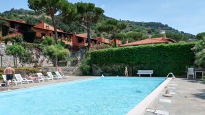 A swimming pool with lounge chairs, a stone deck, and a hillside backdrop. - Bella Vista by Interhome (Ventimiglia)