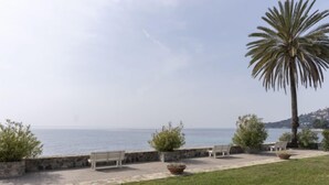 A coastal walkway with benches, a palm tree, and a view of the sea. - Bella Vista by Interhome (Ventimiglia)