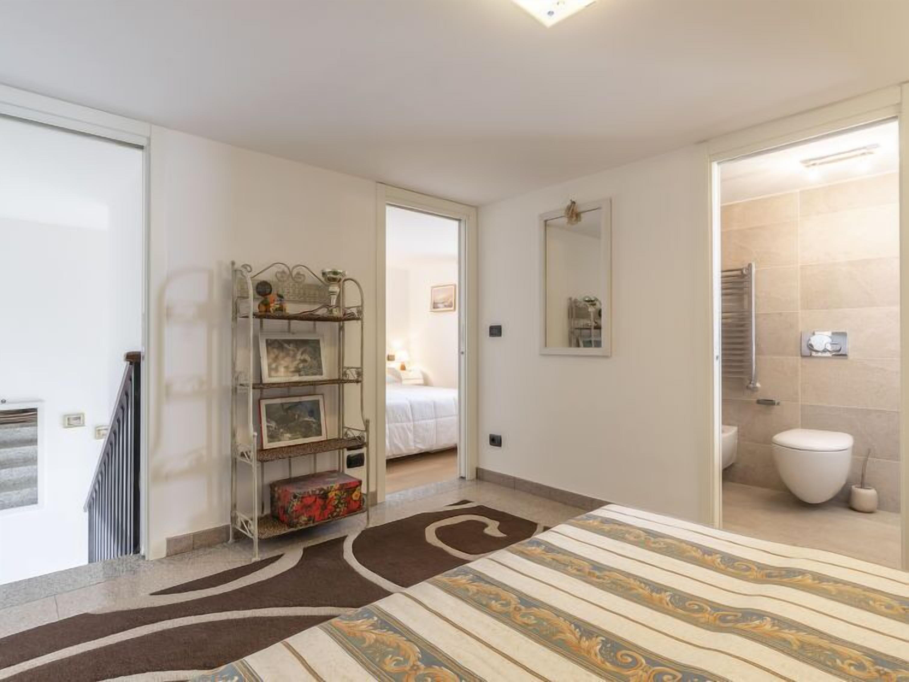 A bedroom with a bed, a bedside table, a mirror, and a wardrobe.