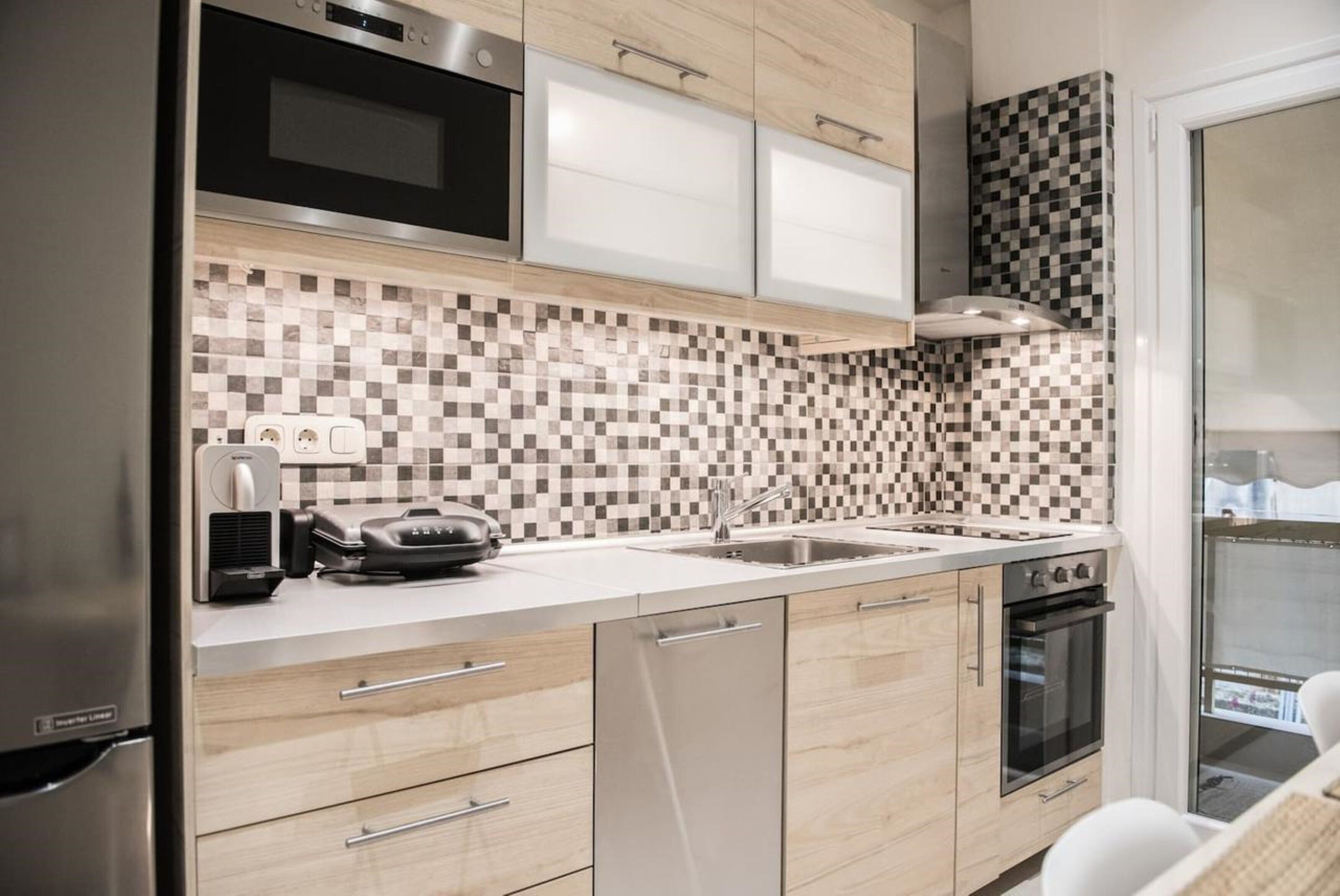 A modern kitchen with a checkered backsplash, stainless steel appliances, and wooden cabinets.